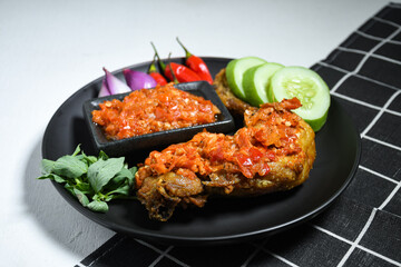 Ayam geprek sambal indonesian food or geprek fried chicken with sambal hot chili sauce on black plate