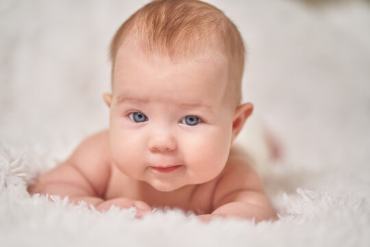 portrait of an infant looking into the camera with sly emotion on a soft blanket
