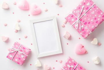 Valentine's Day concept. Top view photo of photo frame pink present boxes heart shaped marshmallow candles and sprinkles on isolated white background with copyspace