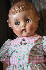 Face of antique doll wearing a white dress with pink flowers.