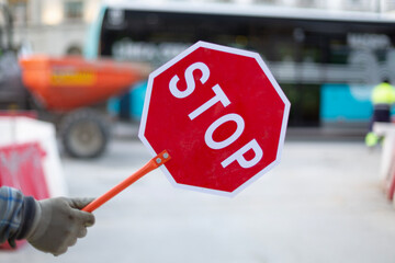 Person directing the traffic for works. Detail of hand holding a stop sign.