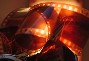 Rolled film strip on warm light background, macro closeup. - 553819344