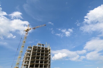 A tower crane builds a residential building against the sky. Construction of buildings, construction site.