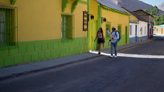 Two latin tourists or backpackers walking through the street of Pisco Elqui exploring and taking photos in Valle del Elqui