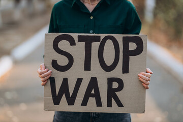 Ukrainian girl protests war, holds banner, placard  with inscription message text Stop War, street...