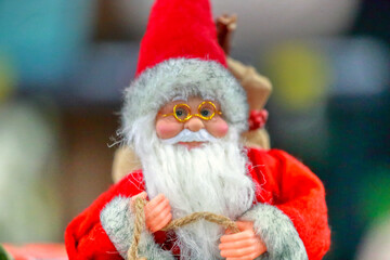 Colorful fun portrait of magical toy Santa Claus. Santa Claus close up looking into camera, festive background, focus in foreground