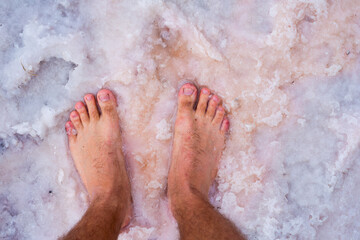 Bare feet on the salt of a dried lake. Spa or travel concept.