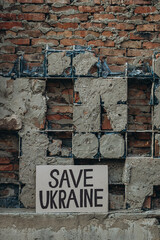 Ukrainian protest against war with banner placard  with inscription message text Save Ukraine, ruined city background. Crisis, peace, Russian aggression invasion concept. anti-war demonstration.