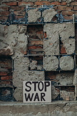 Naklejka premium Ukrainian protest against war with banner placard with inscription message text STOP WAR, ruined city background. Crisis, peace, Russian aggression invasion concept. anti-war demonstration.