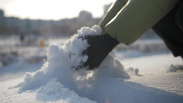 Woman grabbing snow by hand and throws it on top.Slow motion Close-up Girl in winter gloves take snow nature winter concept.