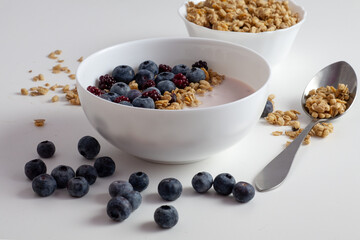 There is a plate of yogurt on the table. Topped with granola and blueberries. Healthy food.