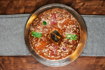 Roscon de reyes with candied fruit, almonds and sugar on top, filled with cream, overhead view