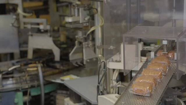 This video shows a mini assembly line of baked goods as they are wrapped and coming off the conveyer belt.