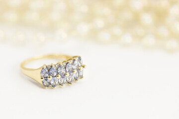 Złoty pierścionek na jasnym tle - złota biżuteria i jasne tło - pierścionek z brylantami