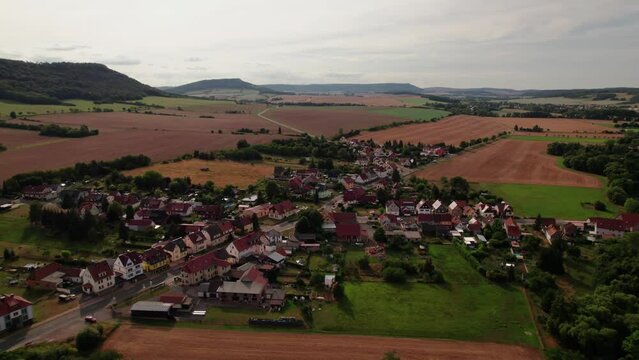 Aer ial view of a German village surrounded by meadows, farmland and forest in Germany.