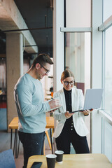 Business people man and woman over coffee discussing business looking at laptop, modern workspace. Colleagues work together in the office