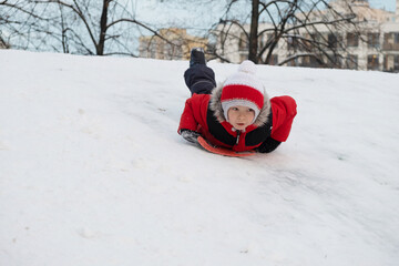 The boy climbs down on a sledge on a hill