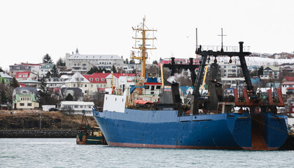 Industrial trawler ship with blue hull stands moored in port