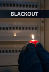 Blackout, standing with a candle in front of a power fuse box, energy cut out, uncertain supply,...