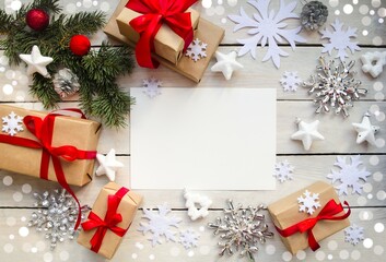 Christmas background, on a wooden table lies a white sheet of paper for copying text, white and silver snowflakes, holiday gifts, a green spruce branch.  Concept holiday Christmas and New Year. 