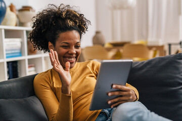 Smiling mixed race woman answers video call using tablet