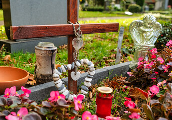 Holzkreuz mit einer schönen Steinkette in Herzform auf einem Friedhof in Hamburg