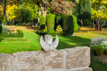 kleiner Engel von hinter mit ausgebreiteten Flügeln auf einer Mauer  auf einem Friedhof in Hamburg