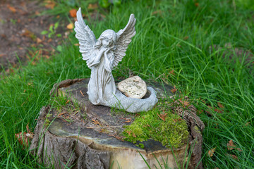 schöner kleiner Engel auf einem  mit Moos bewachsenen Baumstumpf  auf einem Friedhof in Hamburg