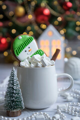 Hot cocoa with marshmallow in a white ceramic mug surrounded by winter things on a wooden table. The concept of cosy holidays and New Year.