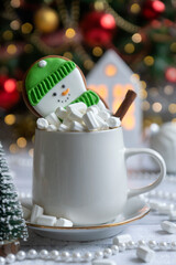 Hot cocoa with marshmallow in a white ceramic mug surrounded by winter things on a wooden table. The concept of cosy holidays and New Year.