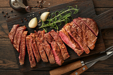 Steaks. Sliced grilled meat steak New York or Ribeye with spices rosemary and pepper on black...