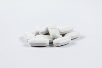many white oval medical tablets for humans and animals, medicinal antibiotics pills medicine closeup