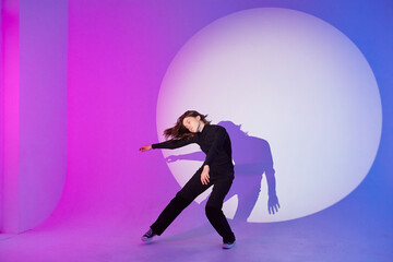 Teenage girl dances in a spotlight. The play of light and shadow.