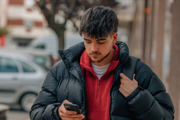 young student with mobile phone in the street in winter clothes
