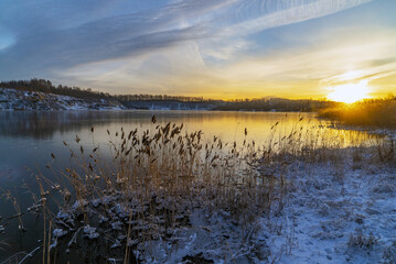 Sunset in winter on the shore of a freezing lake.