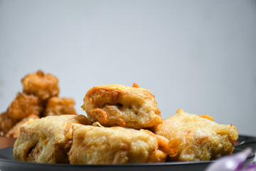 Selective Focus Gorengan or Fried tofu is a type of fried food made from tofu, flour and filled with bean sprouts on a black plate. Fried food is one of the favorite snacks in Indonesia.