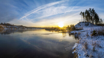 Colorful sunset in winter on the shore of a freezing lake.