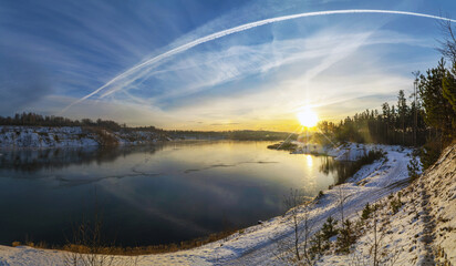 Colorful sunset in winter on the shore of a freezing lake.