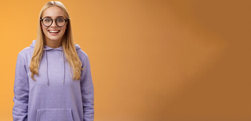 Charming female student geek smiling energized wanna participate university event grinning look excited wearing glasses purple hoodie standing amused orange background having fun - obrazy, fototapety, plakaty