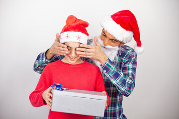 Happy man covering his son's eyes giving a gift for Christmas  isolated on white background