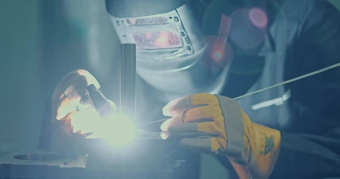 Professional men in welding masks and gloves work in the workshop with arc welding and argon. Close-up