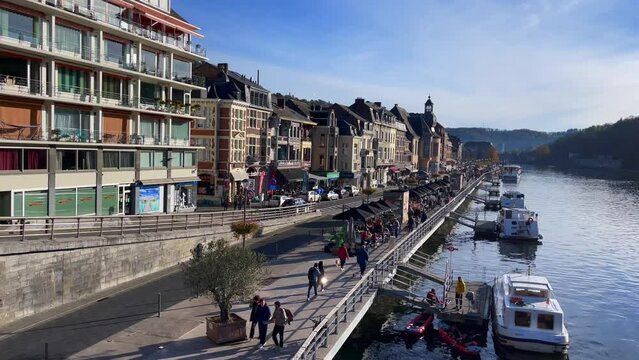 People walking by the Meuse river in Dinant, Belgium