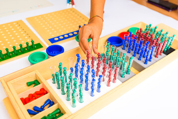 Detail of a montessori board division with the hand of a guide and teacher showing how to perform the operation.