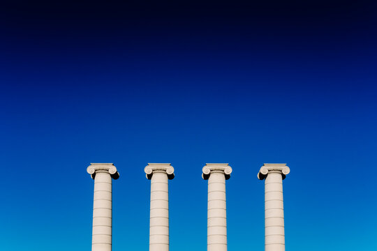 Four classical ionic columns, isolated on blue sky background