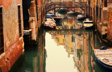 Narrow canal with boats between old houses in Venice, Italy