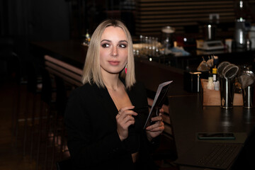 People. Lifestyle. A beautiful business woman has fun chatting online on a laptop at the bar counter in a cafe or restaurant in the evening. Concept