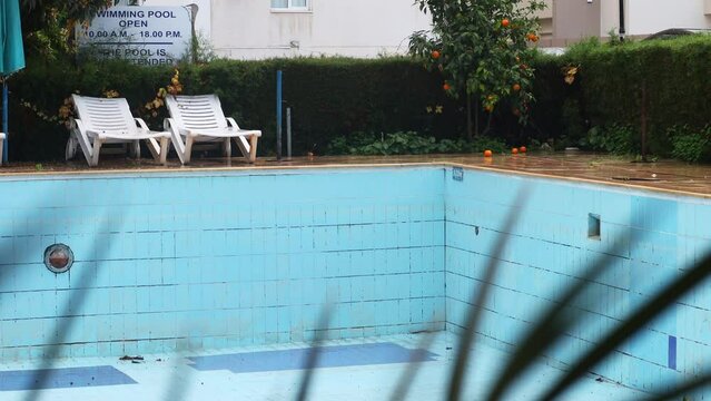 It's raining in a forgotten place on an abandoned blue pool under tangerines