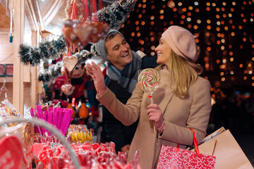 Couple buying sweet at Christmas market. A young couple in love buying christmas candy