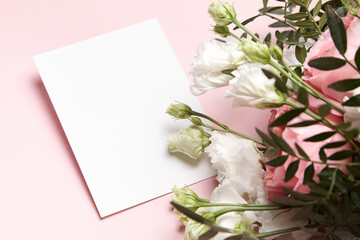 Obraz na płótnie Canvas Holiday greeting card mockup with bouquet of flowers on light pink background. White wedding invitation mockup and floral decor