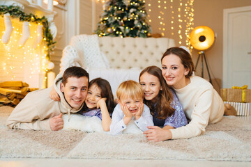 Beautiful happy large family on the floor in room with the Christmas tree.